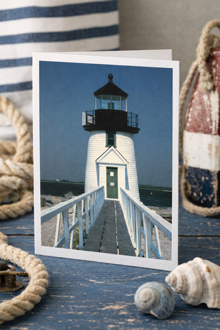Greeting card with a lighthouse on a blue background, surrounded by nautical items.