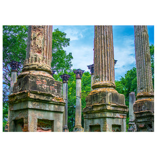 Ruins of classical columns with greenery and blue sky in the background