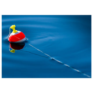 Red and yellow Fishing Bobber floating on blue water.