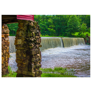 Stone dam with water flowing over it, surrounded by greenery