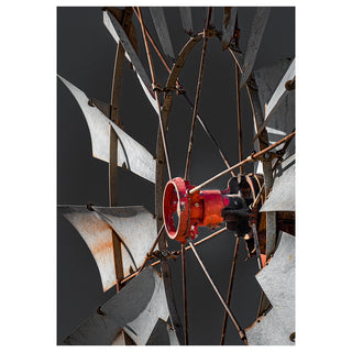 Close-up of a rusted metal windmill with a red center against a dark background