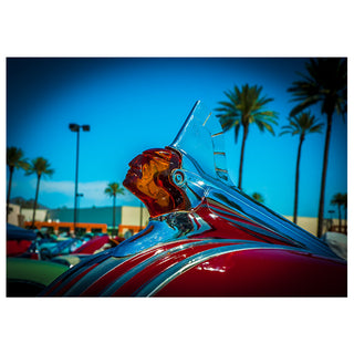 Close-up of a vintage Pontiac hood ornament with palm trees in the background