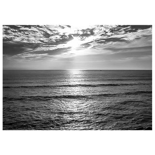 Black and white photograph of a sunlit ocean with clouds.
