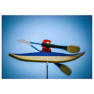 Model of a person in a kayak with a paddle against a blue background