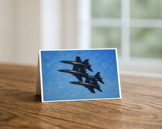 Blue Angels oil painting 5x7 greeting card from Will Davis Studios displayed standing on a wooden table near a bright window — four US Navy F/A-18 Hornets in tight stepped formation with blue and gold paint scheme, naval aviation fine art card