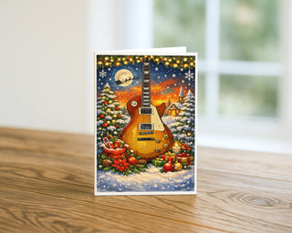 Electric guitar Christmas greeting card displayed on a wooden table with snowy winter scene, holiday lights, gifts, and Santa’s sleigh, festive music card by Will Davis Studios.