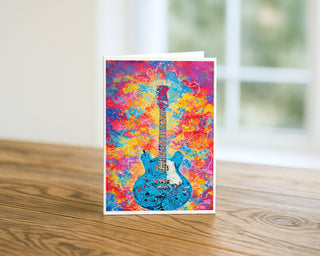 Colorful funky blue guitar abstract art greeting card standing on a wooden table, vibrant music-themed 5x7 card by Will Davis Studios.
