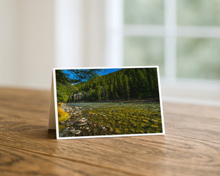 5x7 greeting card featuring a scenic Montana river with clear water, rocky shoreline, and evergreen forest landscape, fine art photography by Will Davis Studios.