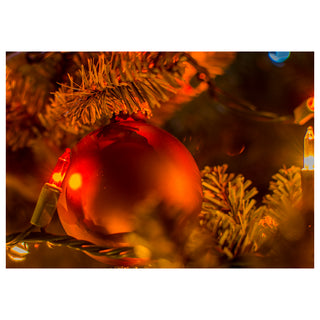 Fine art greeting card featuring a glowing red Christmas ornament nestled in fragrant evergreen branches surrounded by warm amber twinkling holiday lights that blur and glow like tiny captured stars, rendered in rich deep tones of crimson, gold, and pine green that radiate the cozy magic of the holiday season, 5x7 blank card with envelope by Will Davis Studios.