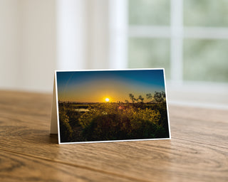 Greeting card with a sunset landscape on a wooden surface by Will Davis Studios