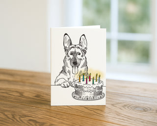 Greeting card with a drawing of a dog and birthday cake on a wooden surface.  Will Davis Studios