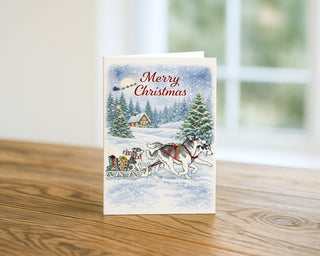 Christmas card with a Siberian Husky dog sled scene on a wooden surface Will Davis Studios