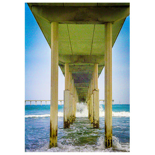 Underneath a pier with ocean waves crashing against it