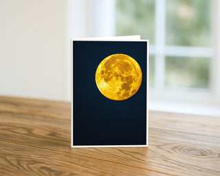 Greeting card with a full moon design on a wooden surface Will; Davis Studios