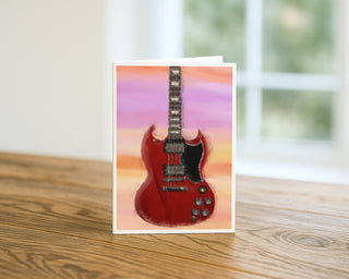 Greeting card with a red electric guitar design on a wooden surface Will Davis Studios