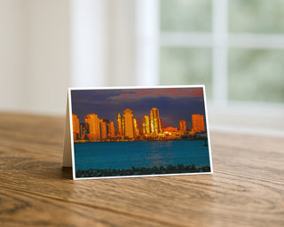 Greeting card with a cityscape at sunset on a wooden surface by Will Davis Studios