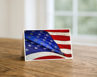 American flag-themed greeting card on a wooden surface with a blurred background by Will Davis Studios