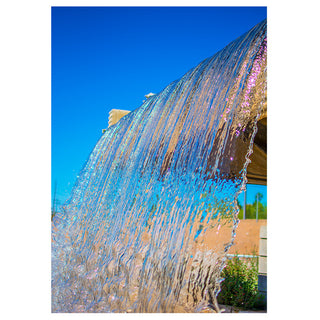 Fountain with water spraying upwards against a clear blue sky 